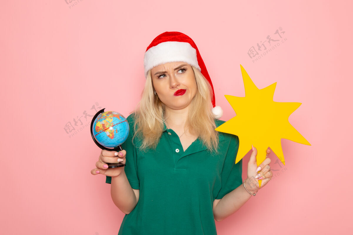 肖像正面图年轻女性手持地球仪和黄色人像在粉色墙壁上模特女性圣诞假期照片新年色彩身材颜色圣诞节