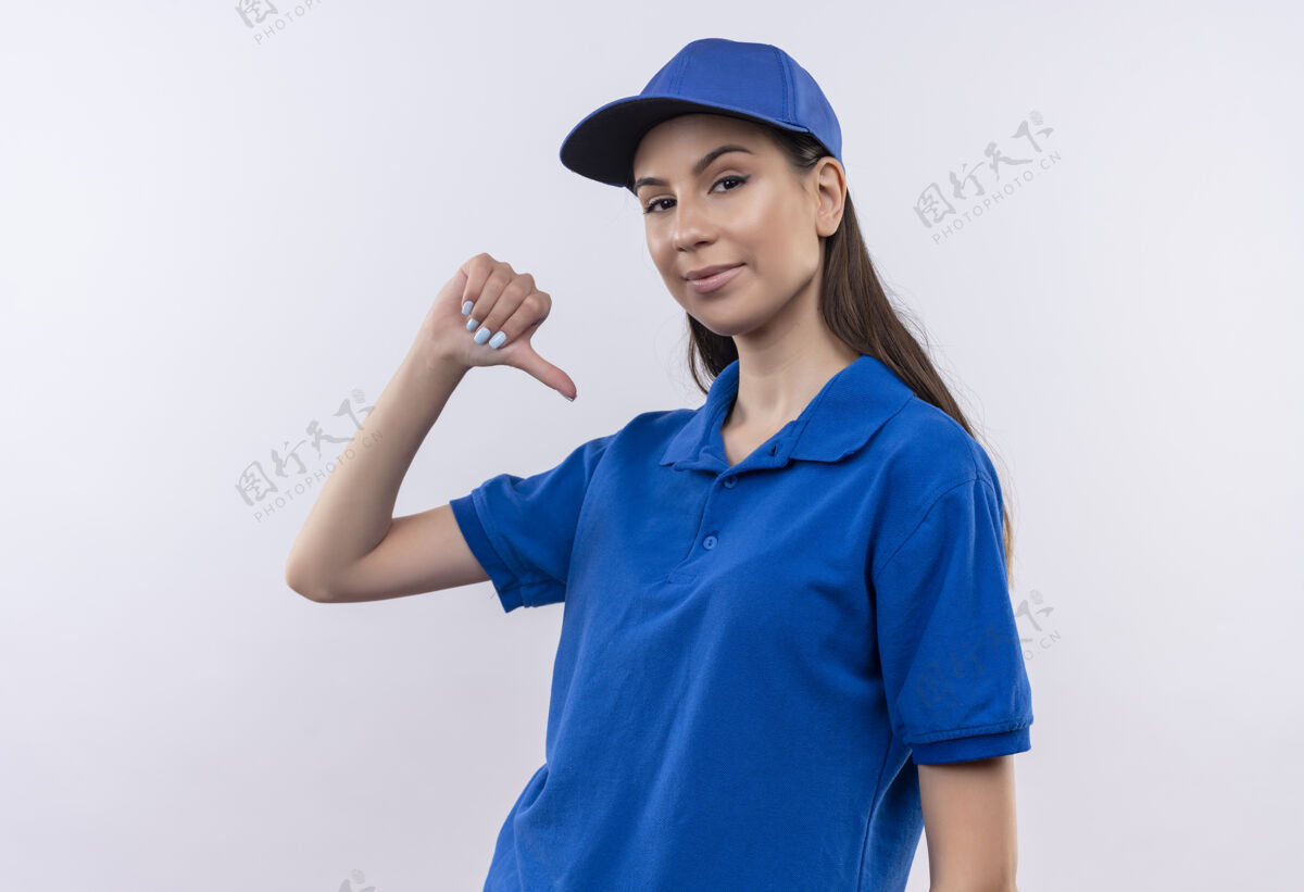 蓝色穿着蓝色制服 戴着帽子的年轻送货女孩指着自己 自鸣得意 骄傲自大自我满足年轻她自己