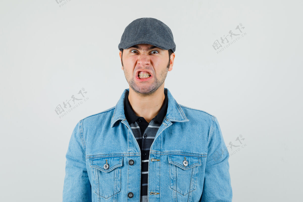 男性戴帽子 穿t恤 穿夹克的年轻人咬牙切齿 看上去很生气发型牙齿现代