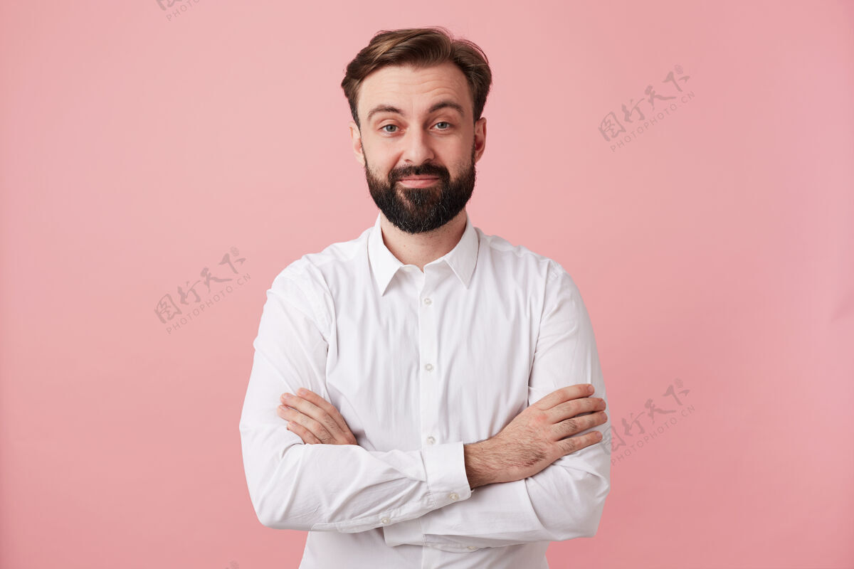 商人摄影棚拍摄了一个正面的年轻黑发男人 留着胡子 留着时髦的发型 面带微笑 穿着正式的衣服 在粉红色的墙上摆姿势理发黑发帅气