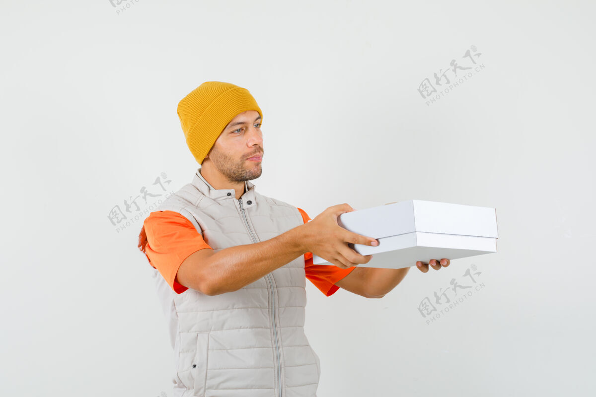 胡茬穿着t恤 夹克 帽子的年轻人送纸板箱 看上去很文雅 正面照自信帽子成人