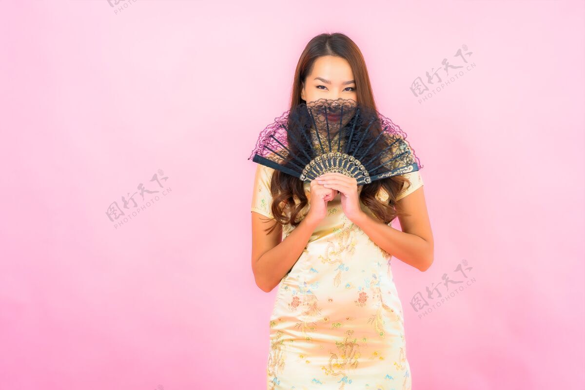 女孩用中国新年概念和彩墙扇子描绘美丽的亚洲年轻女子模特女性文化