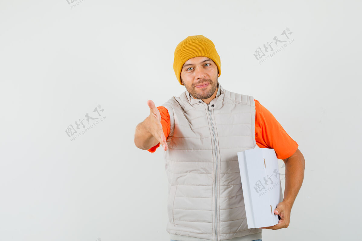帽子年轻人举手握手 手里拿着一个装着t恤衫 夹克衫 帽子的纸板箱 看上去很文雅正面图衬衫年轻英俊