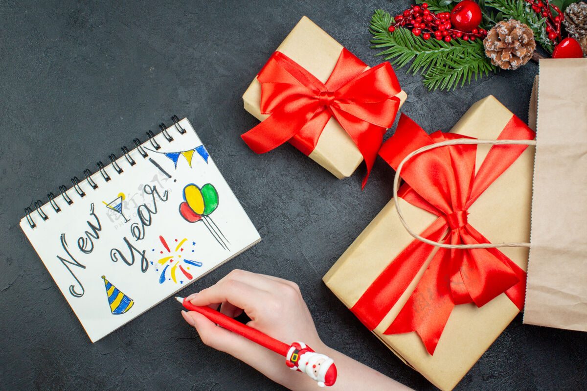 针叶树上图是圣诞气氛 美丽的礼物和冷杉枝 针叶树 圆锥体 笔记本旁边是黑色背景上的新年图画绘图圆锥体心情