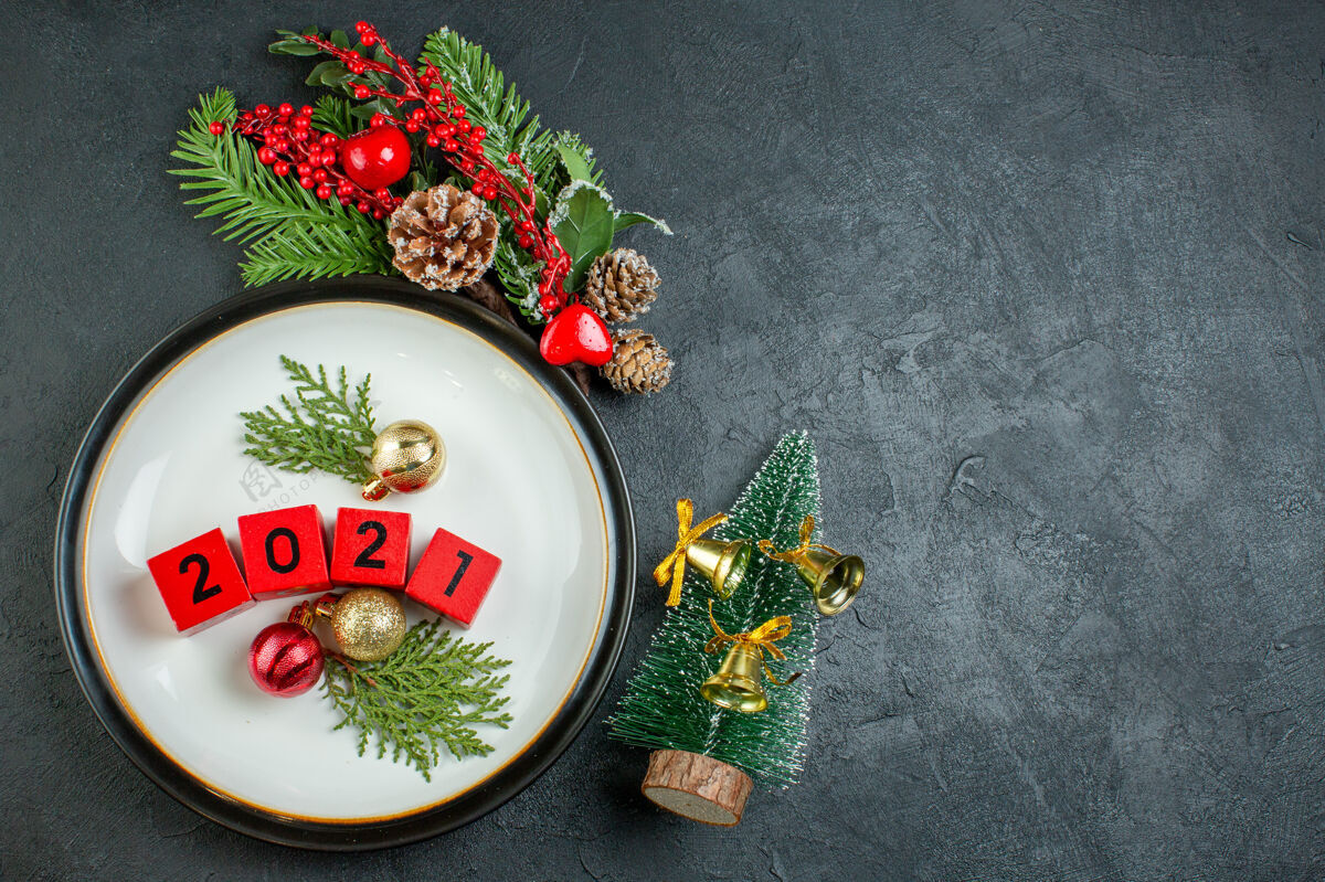 饮食俯视图上的数字装饰配件板冷杉树枝针叶树圆锥旁边的圣诞树上的黑暗背景圆锥体托盘圣诞