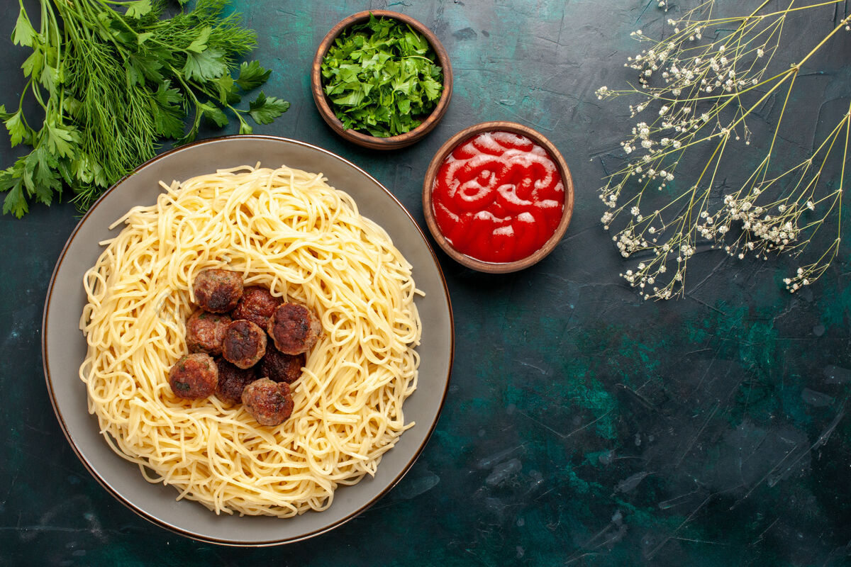 意大利面俯视图煮熟的意大利面食 深蓝色表面有肉 番茄酱和绿色烹饪肉食物