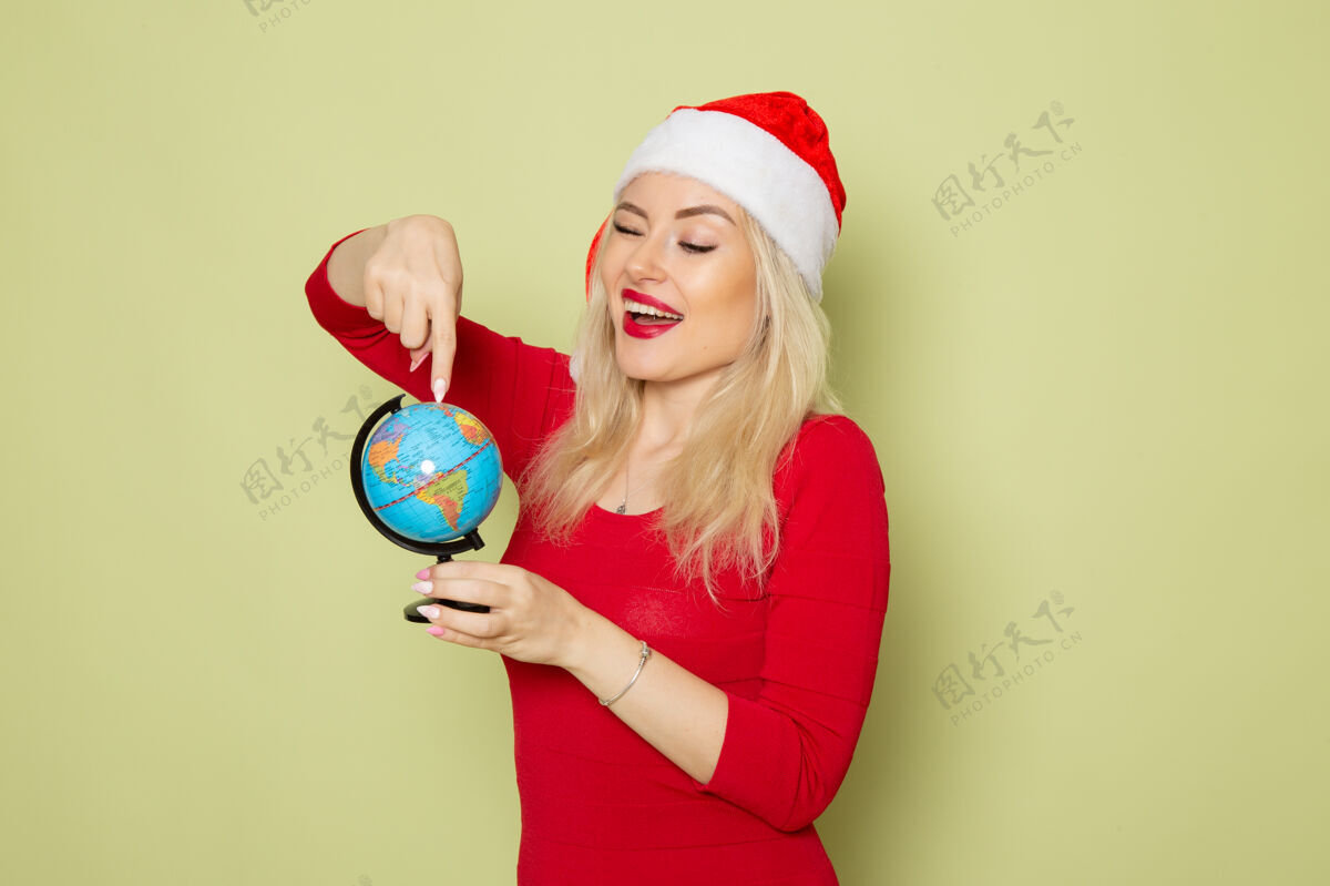 高尔夫球手前景靓女抱着小地球仪在绿墙上度假圣诞雪新年情感色彩漂亮颜色圣诞节