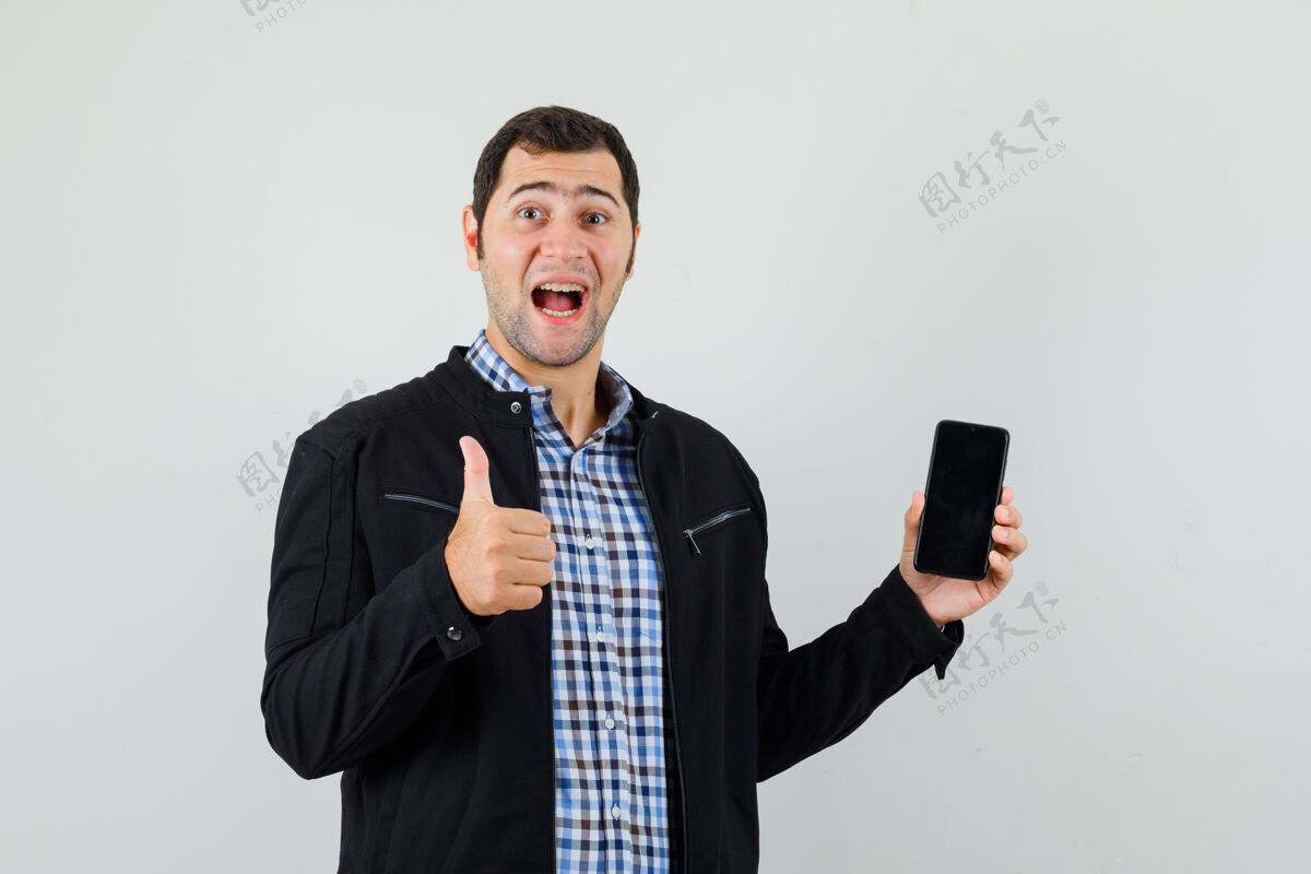 抱年轻人拿着手机 在衬衫 夹克衫上竖起大拇指 看上去很高兴衬衫夹克男性