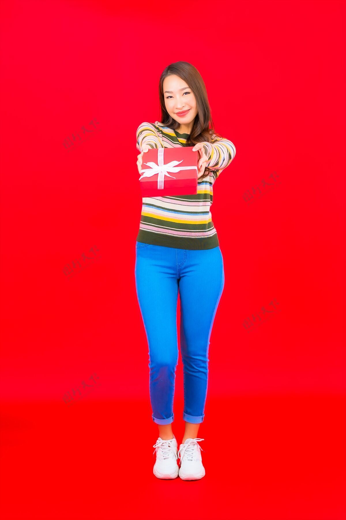 微笑在红墙上画一幅美丽的亚洲年轻女子 带着红色礼盒越南亚洲人时尚