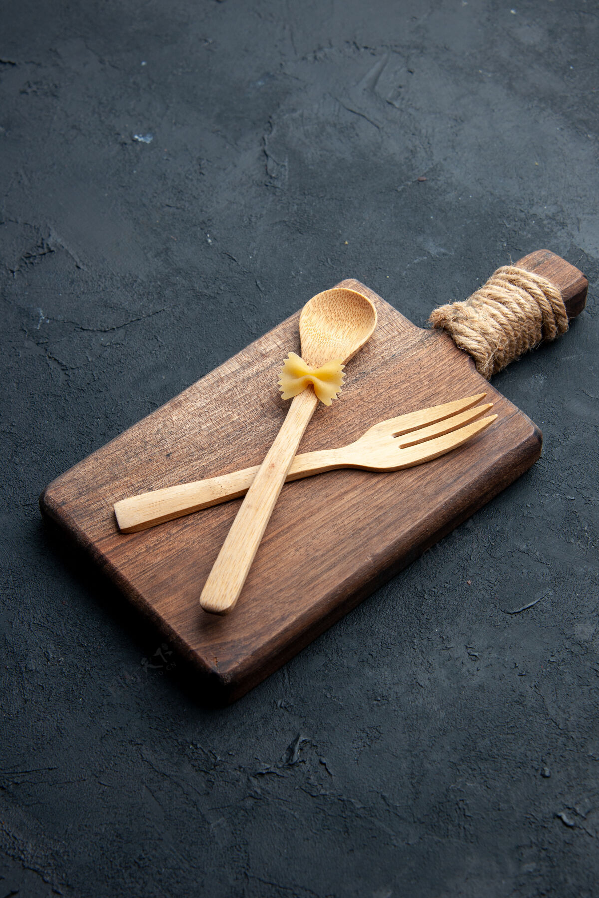 棍子底视图交叉木勺和叉子上的木制服务板在黑暗的表面十字架板木制服务板