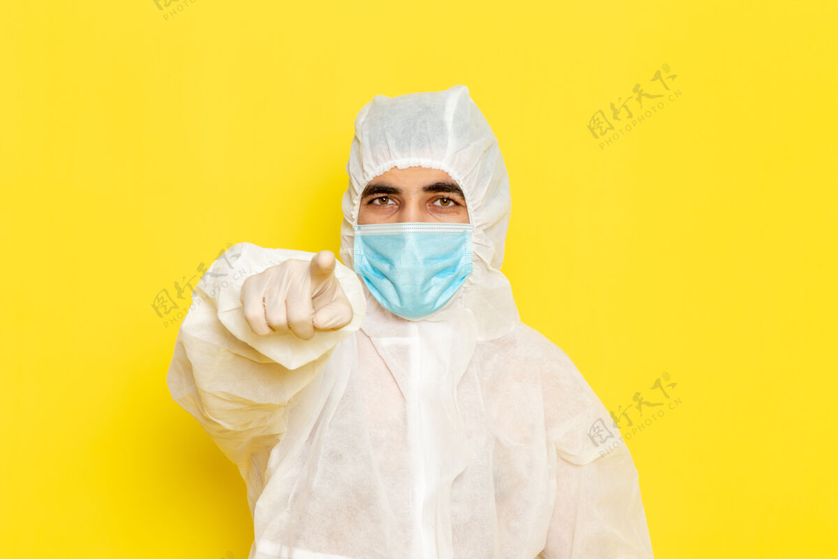 科学身穿白色防护服 带面罩的男性科学工作者的正面图 浅黄色的墙上正面面罩特殊