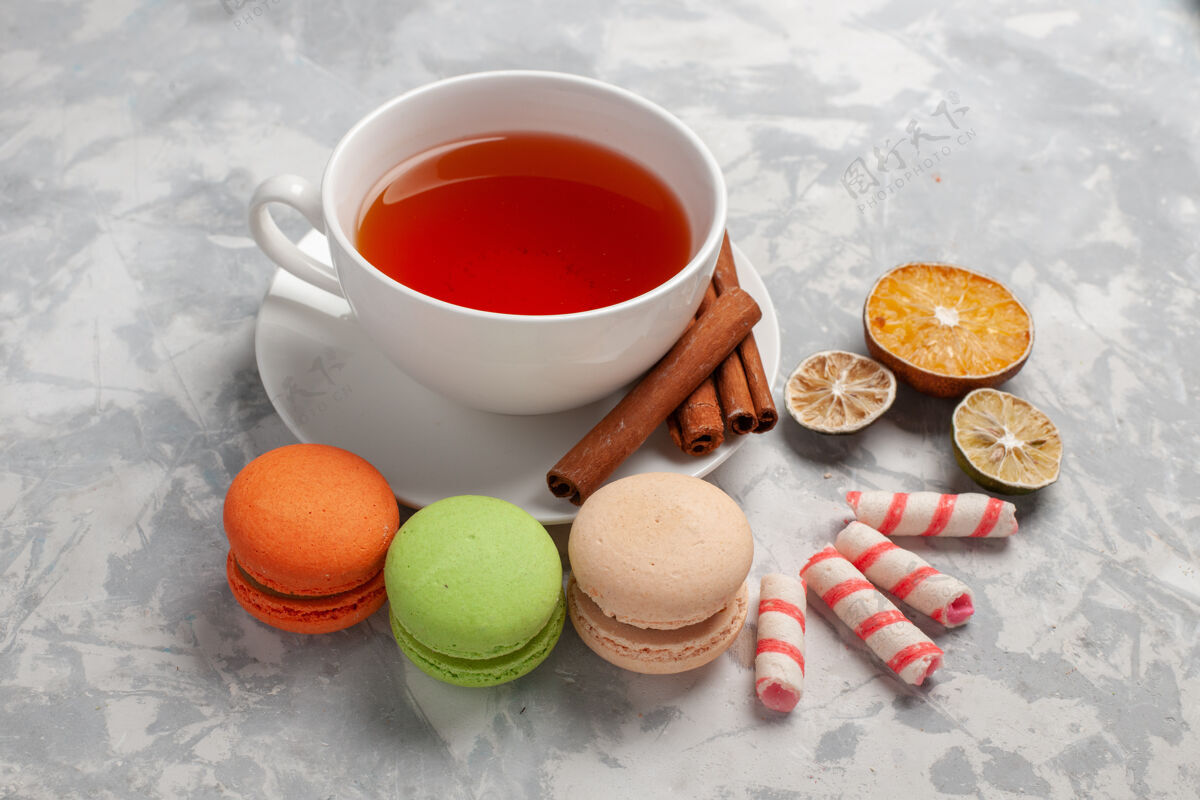 饮料前视图-一杯茶和法国马卡龙放在浅色的桌子上饮料茶容器