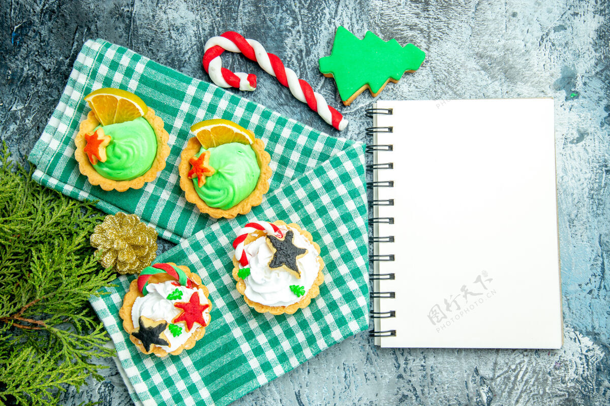 书签顶视图小圣诞馅饼在桌布松枝圣诞糖果记事本在灰色的桌子上小糖果卡片