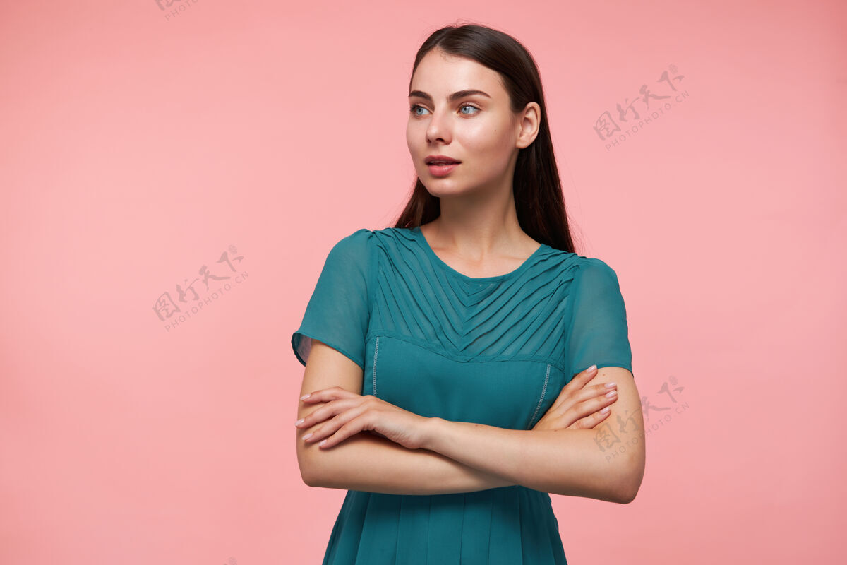 年轻十几岁的女孩 快乐的女人 深褐色的长发双手放在胸前穿着翡翠色的裙子看着左边的粉彩墙上的复制空间手臂女士手