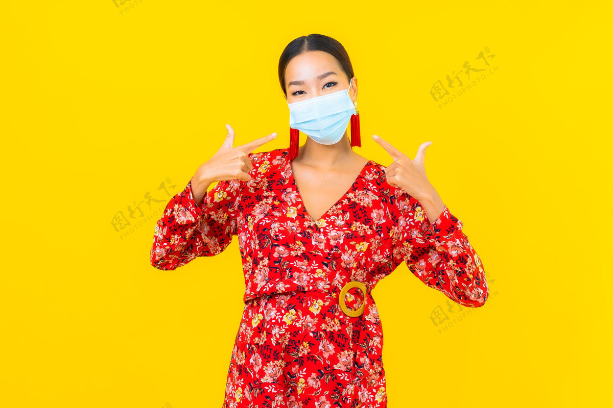 危险肖像美丽的亚洲年轻女子戴上防冠状病毒或冠状病毒的面具在黄色的墙上病人女人空气