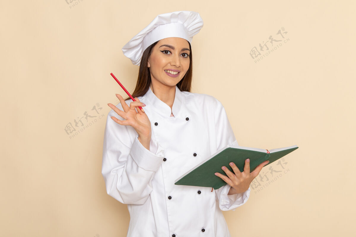 工作身穿白色厨师服的年轻女厨师手持抄写本 微笑着站在浅白的墙上烹饪烹饪护士