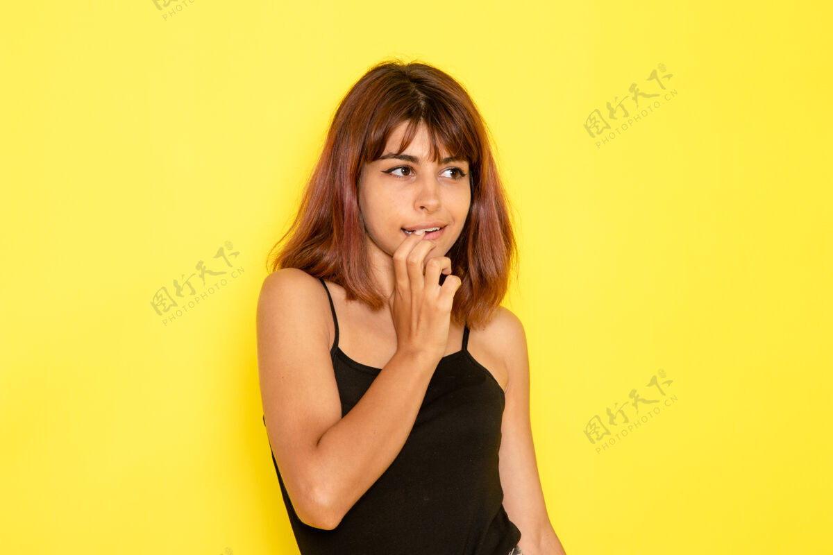衬衫身穿黑色衬衫和灰色牛仔裤的年轻女性在黄色墙壁上摆姿势的前视图情绪姿势牛仔裤