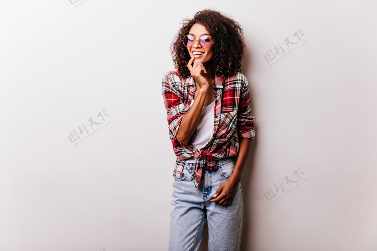 女人穿着复古牛仔裤的漂亮黑人女模特微笑着顽皮的非洲女士的肖像穿着红色格子衬衫快乐人快乐