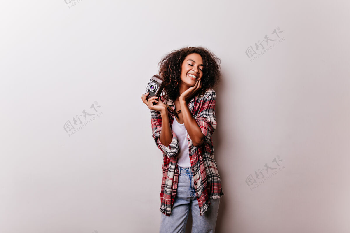 配饰迷人的女摄影师快乐的摆姿势可爱的非洲女士站在白色的相机上笑着女性肖像游戏