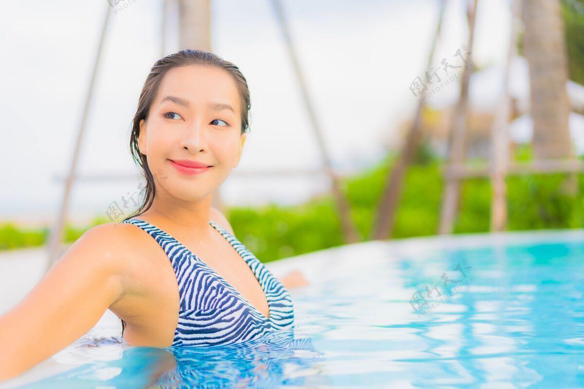 治疗肖像美丽的亚洲年轻女子放松休闲周围的室外游泳池与海洋海滩阳光年轻人蓝色