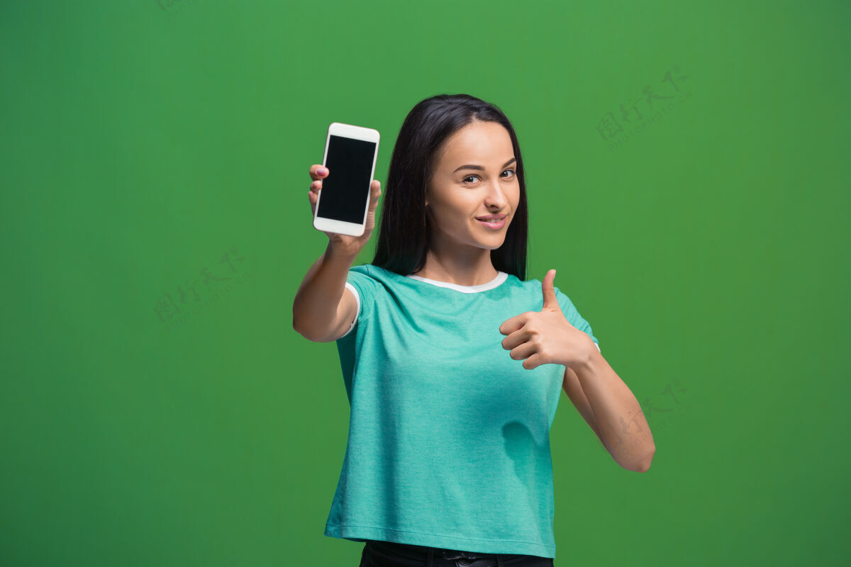 红色一个微笑的女人在绿色的智能手机空白屏幕上展示的肖像手机智能肖像