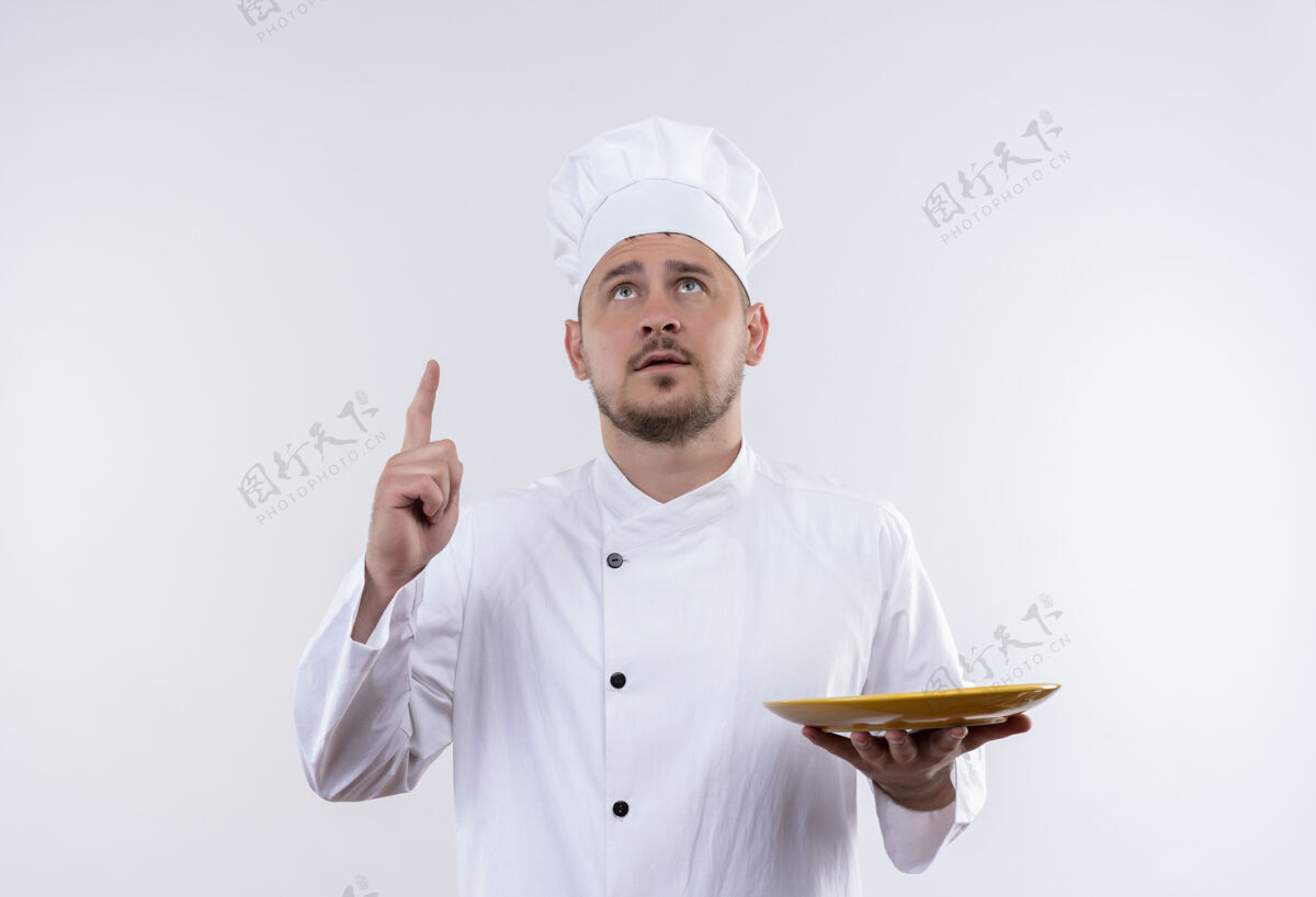 帅气体贴的年轻帅哥厨师 身着厨师制服 拿着盘子 抬头看着与世隔绝的白色空间拿着向上年轻