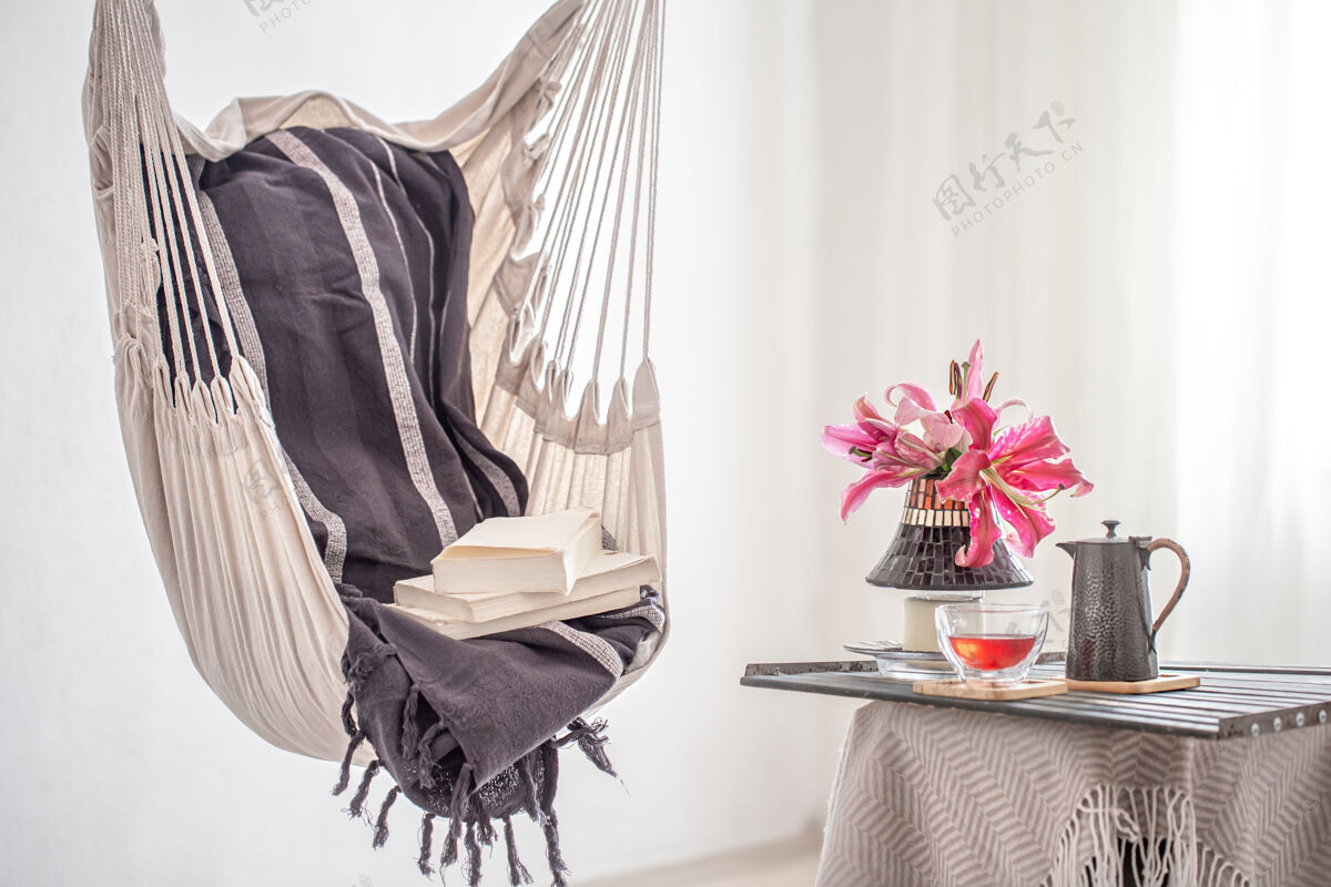 地方波西米亚风格的吊床椅 带书 茶壶和一杯茶休息和家庭舒适的概念文学花花束