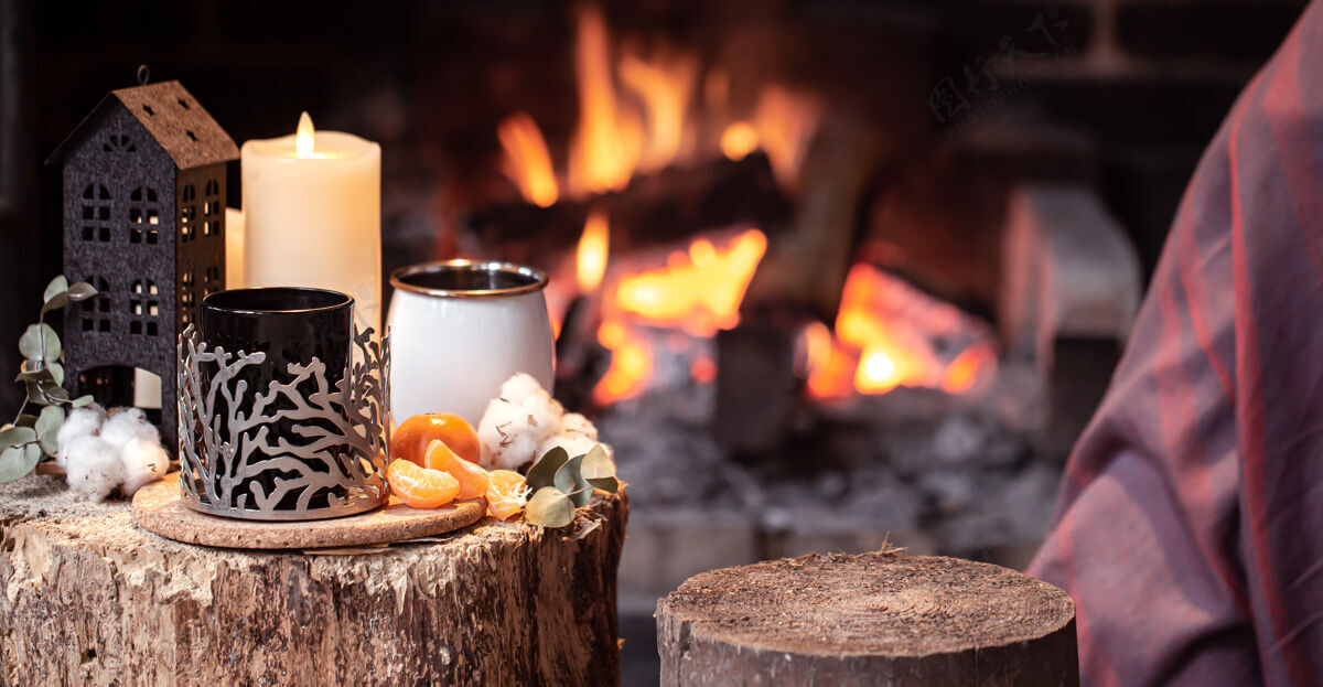 休息在燃烧的壁炉上放上一个杯子 蜡烛和橘子 这是一幅温馨的作品乡村杯子火