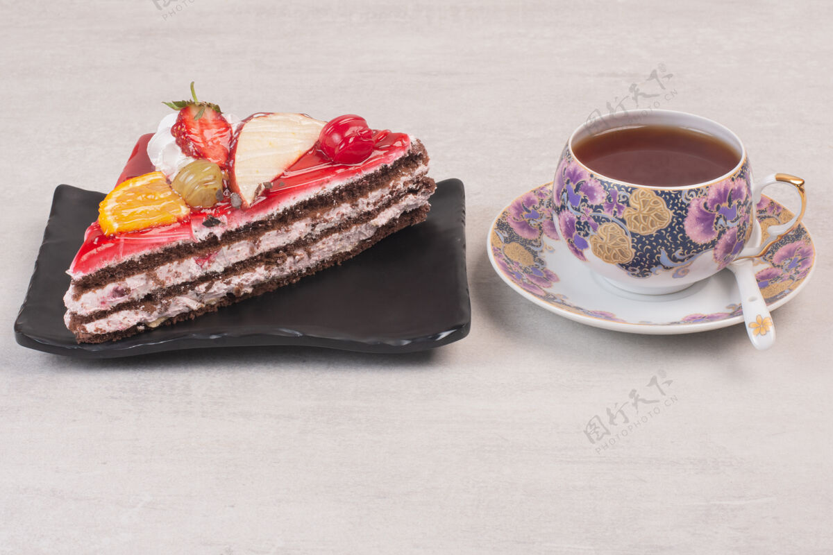 甜点在盘子里放一片巧克力蛋糕 配上水果片和一杯茶切片蛋糕面包房