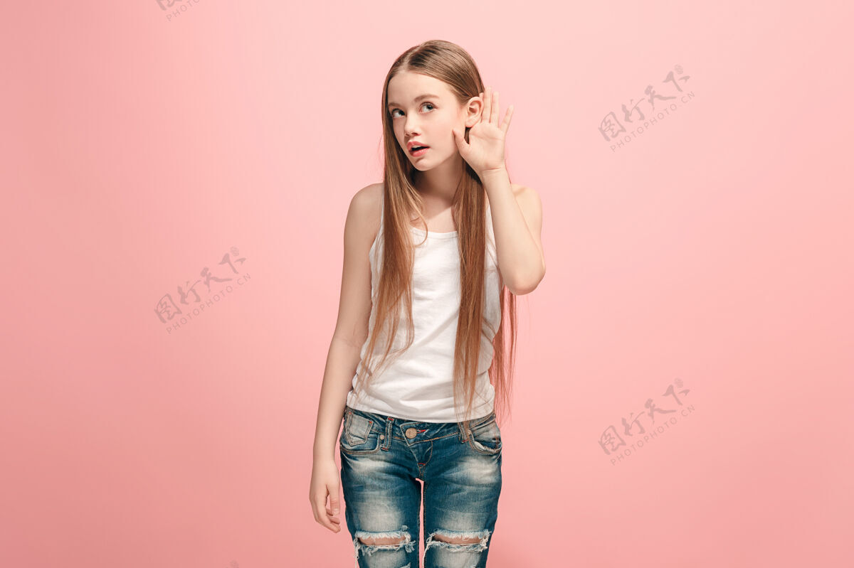 注意力快乐的少女站在时尚的粉红色上聆听美丽的女性半身像耳朵听听