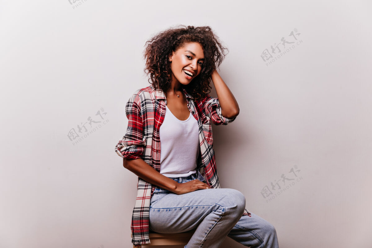 成人优雅的女人穿着复古的蓝色牛仔裤微笑着时尚的非洲女孩穿着休闲装享受拍摄卷发快乐年轻