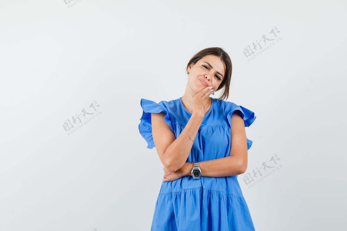 快乐年轻女子穿着蓝色的裙子站在思考的姿势 看起来很漂亮美丽漂亮微笑