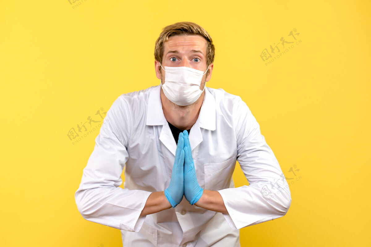 看正面图黄色背景上的男性医生在祈祷的姿势大流行的医疗卫生covid-视图医生外套