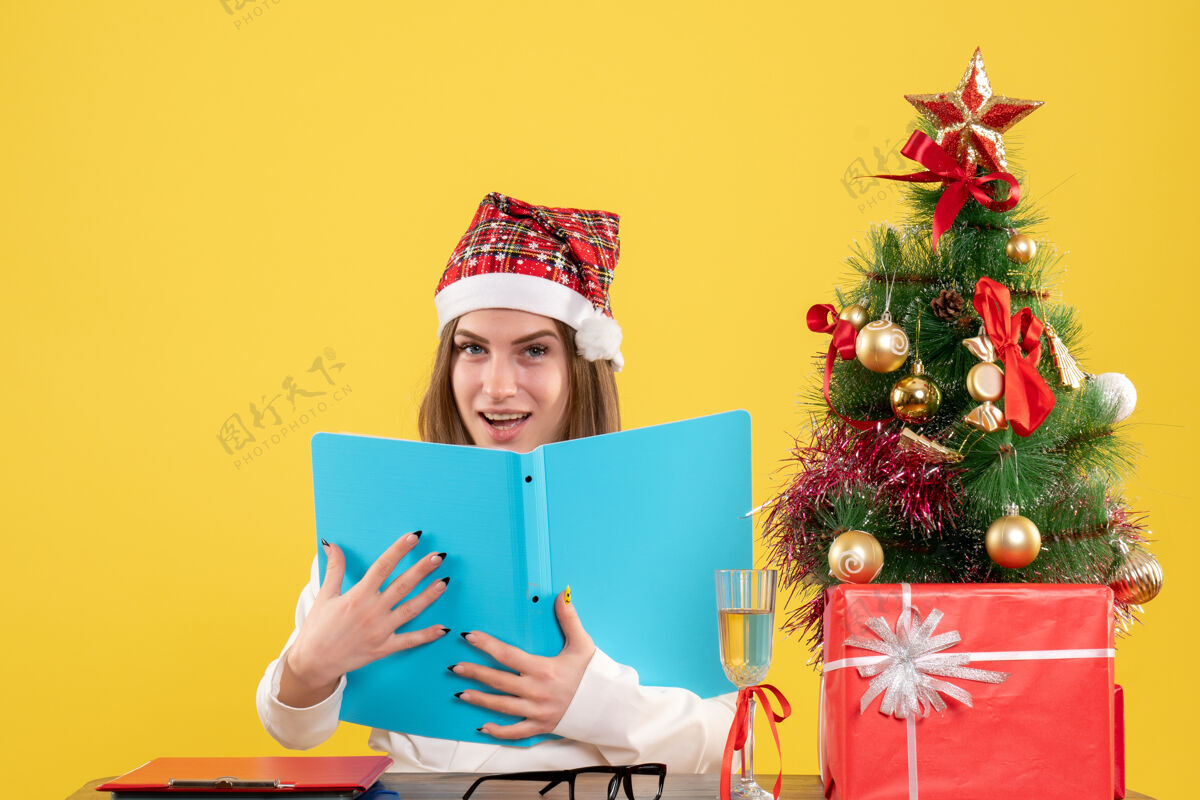 圣诞节前视图女医生坐在圣诞礼物持有黄色背景文件女医生盒子坐着