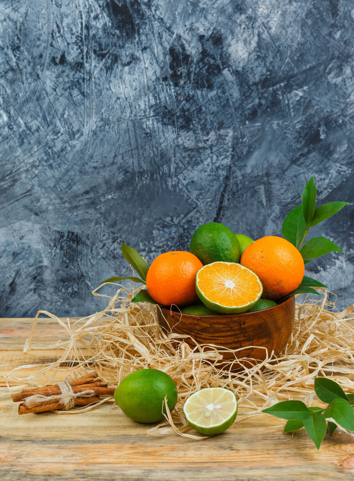 健康木碗里的橘子俯视图 肉桂 酸橙和树叶放在木板和蓝色大理石表面酸橙甜有机