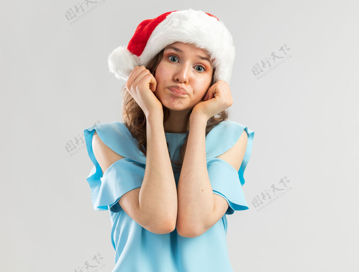 失望身穿蓝色上衣 头戴圣诞帽的年轻女子神情困惑 嘴角歪歪扭扭 表情失望女人顶快乐