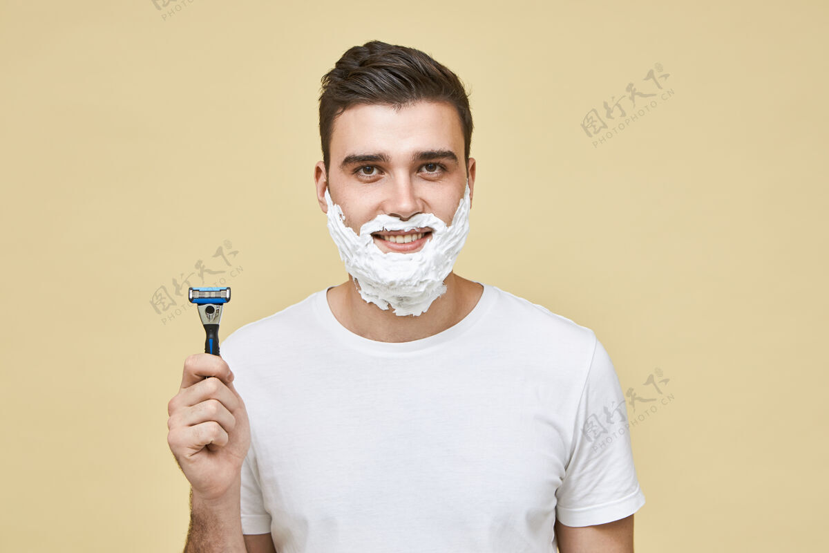 卫生滑稽帅气的年轻男性 脸上有白色泡沫 微笑着 拿着剃须棒 去刮胡子 做早操梳妆和男人的美丽浴室年轻头发