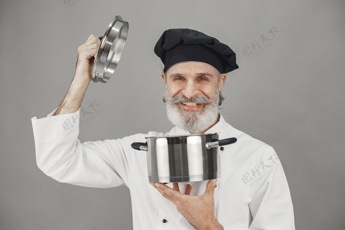 帅气戴着金属锅的高级男人戴着黑帽子的厨师烹饪手美食