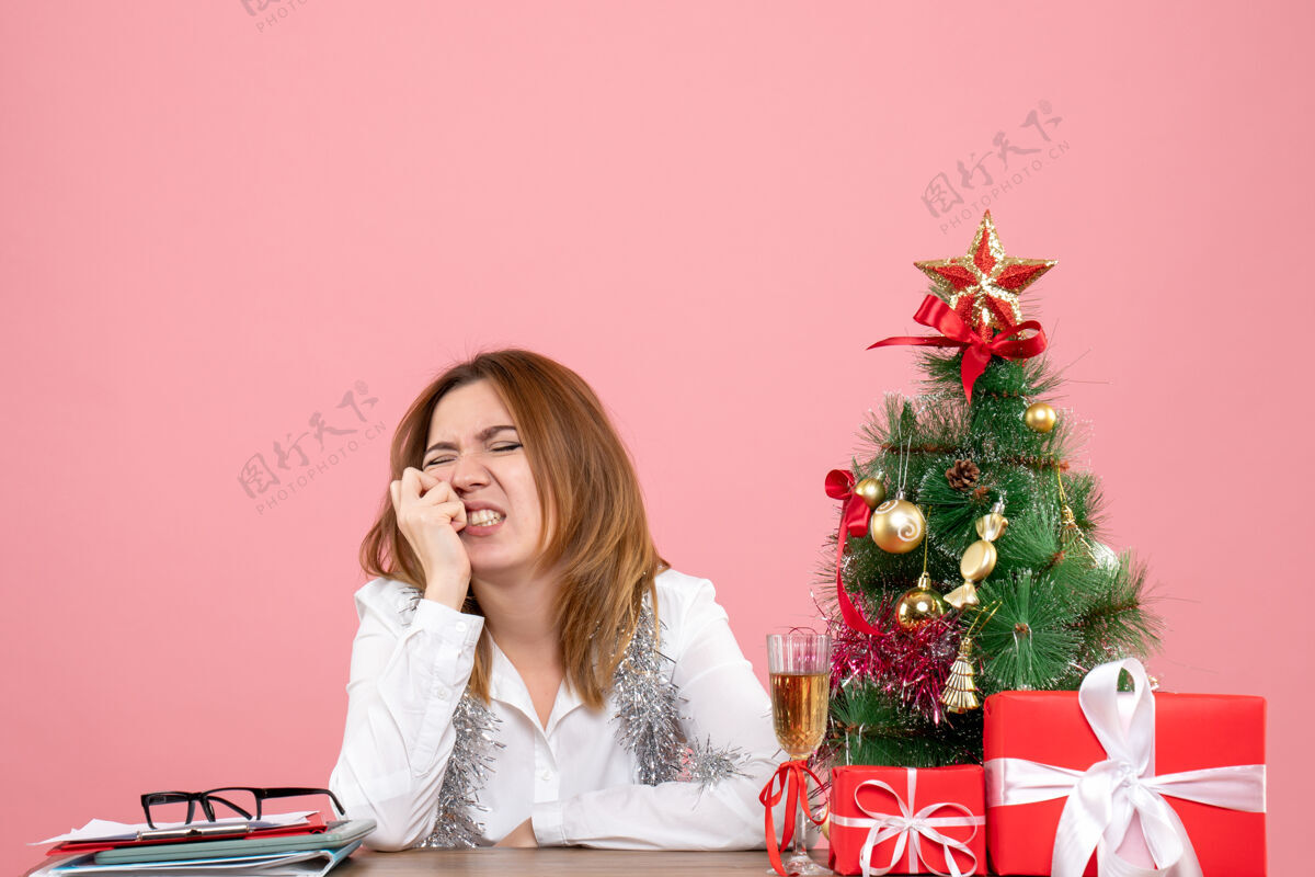 女工人女工坐在桌子后面的正面图 粉色的礼物圣诞节坐情感