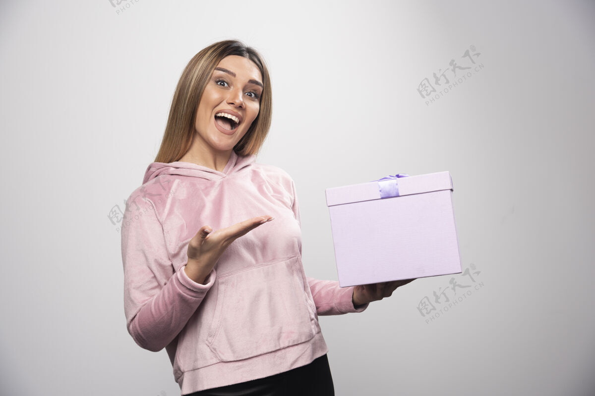 成人穿着运动衫的金发女孩收到了一个礼盒 她感到非常惊喜员工快乐人
