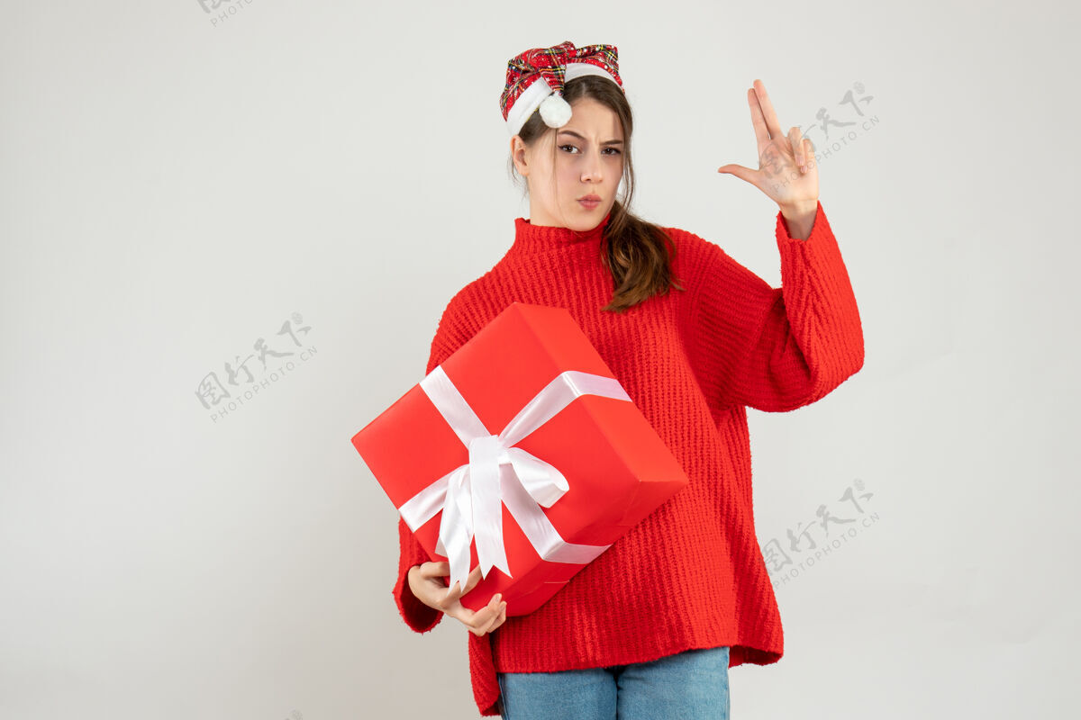 圣诞节戴着圣诞帽的快乐女孩拿着在白色上做礼物的手指枪圣诞老人快乐使