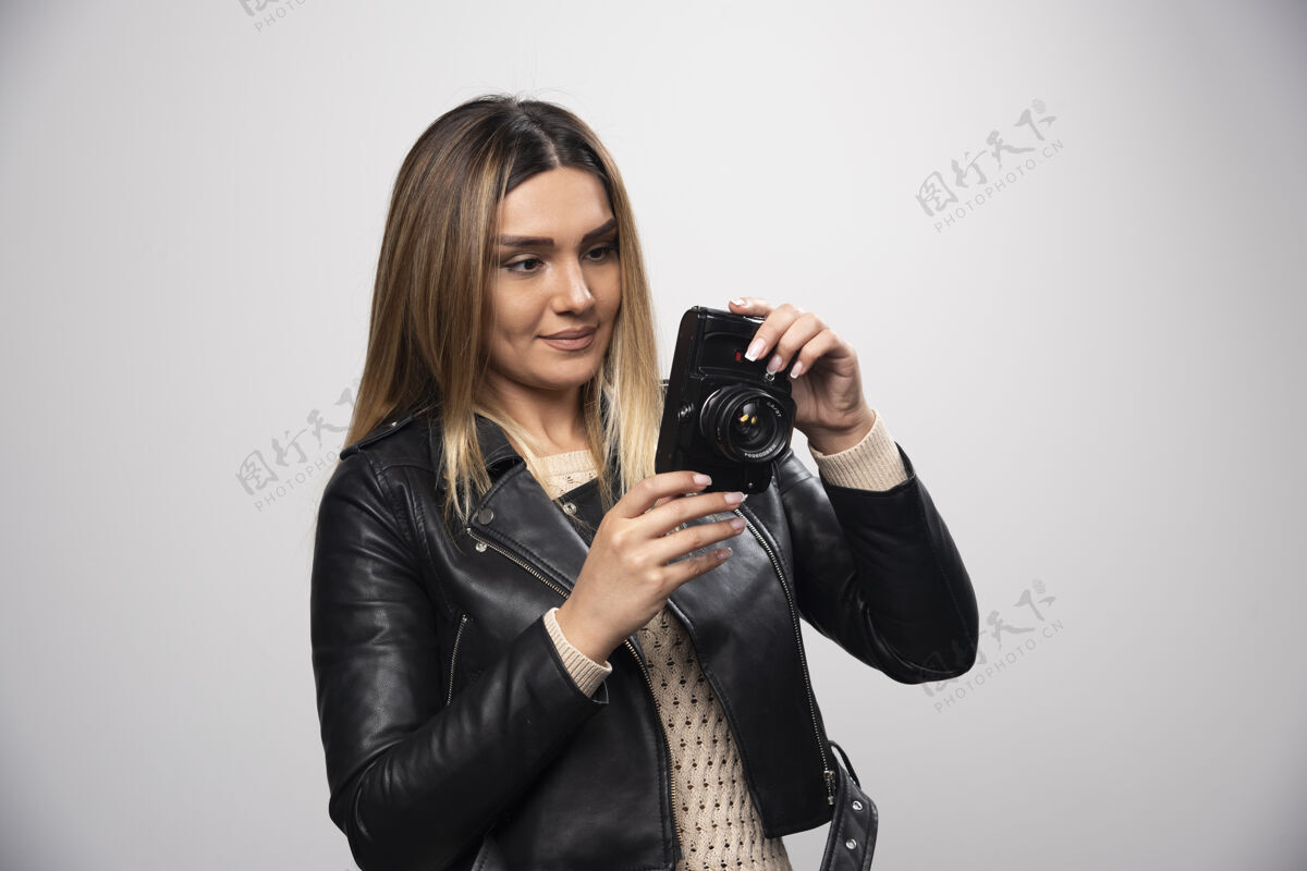 摆姿势穿皮夹克的女孩在照相机上查看她的照片记录会议女人年轻人