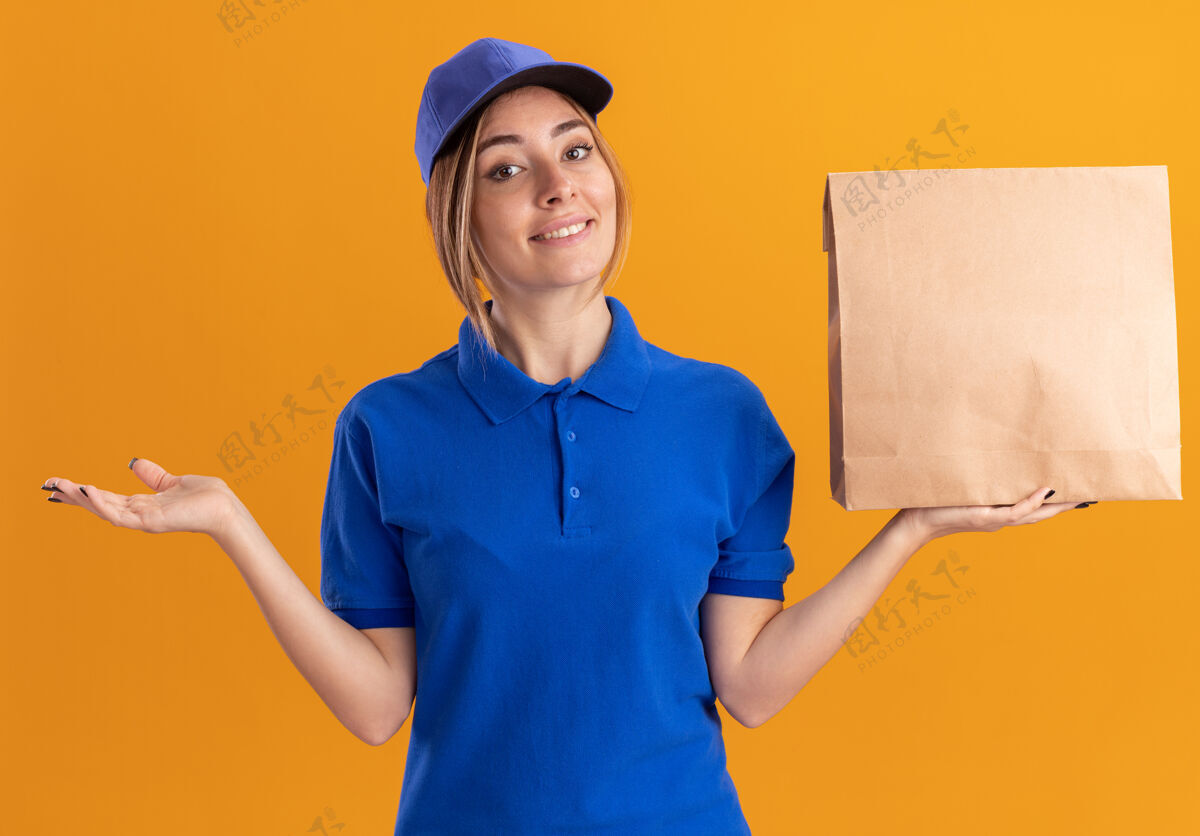 纸微笑着的年轻漂亮的女送货员 穿着制服 手张开 手里拿着纸包裹年轻手制服