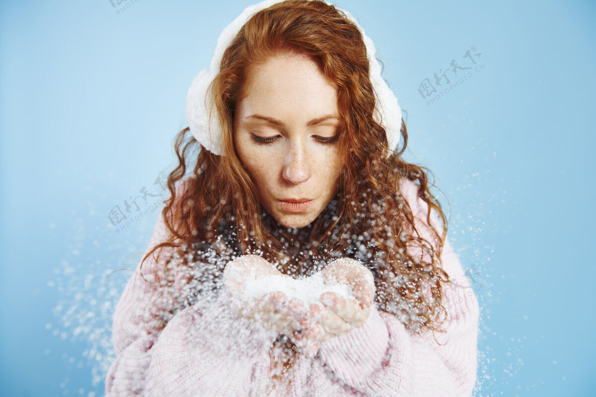 手在摄影棚吹假雪的年轻女子温度幸福寒冷