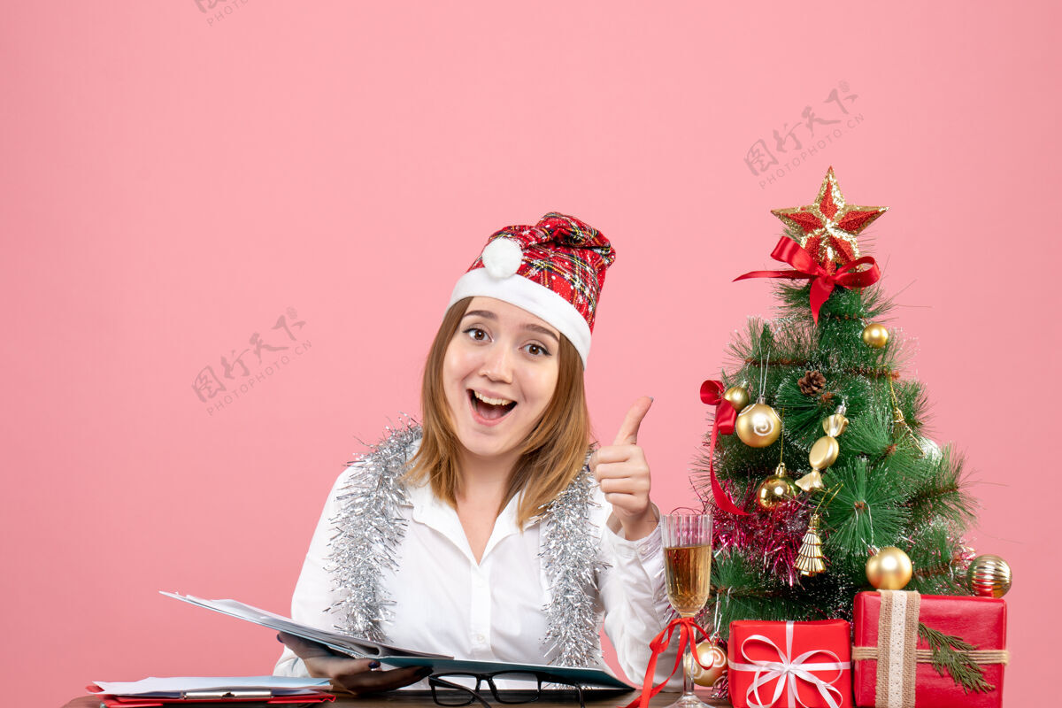 圣诞节女工在粉色地板上查看文件的正面图人办公室工作