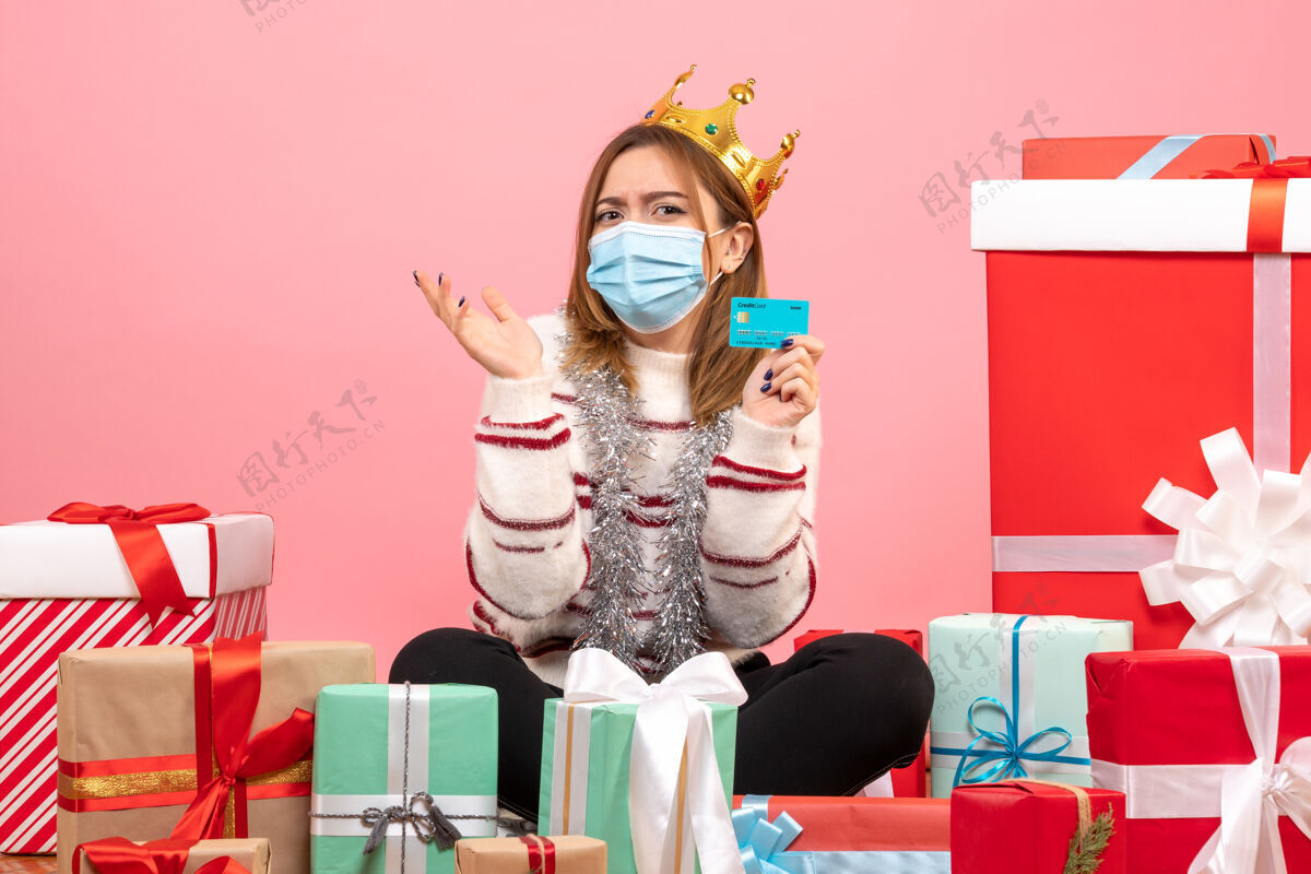 庆祝正面图：年轻女性拿着银行卡围坐在圣诞礼物旁坐着女性卡片