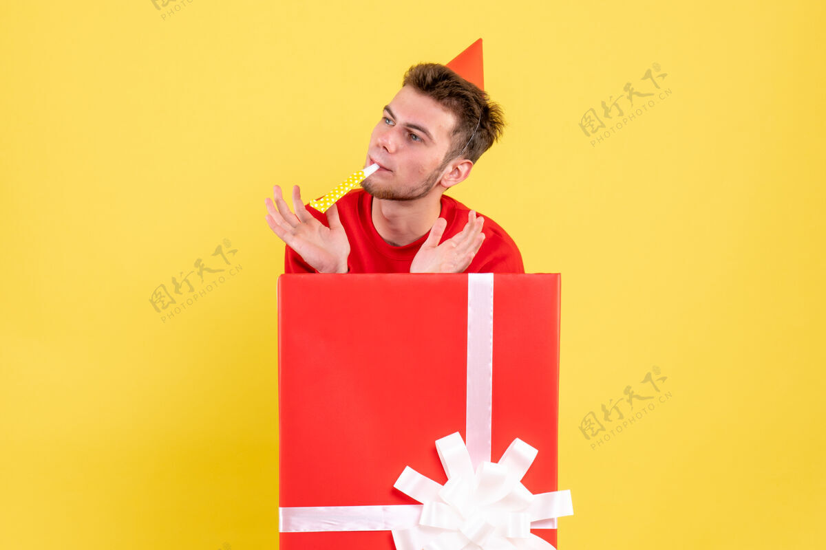 年份正面图穿红衬衫的年轻男子坐在礼品盒内雪盒子圣诞节