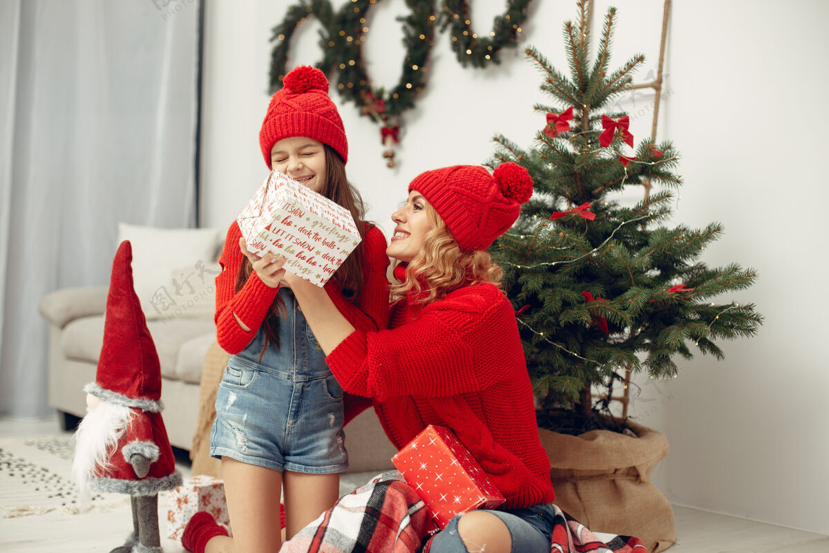 孩子人们在为圣诞节做准备母亲在和女儿玩耍一家人在节日的房间里休息孩子穿着红色毛衣亮光节日花环