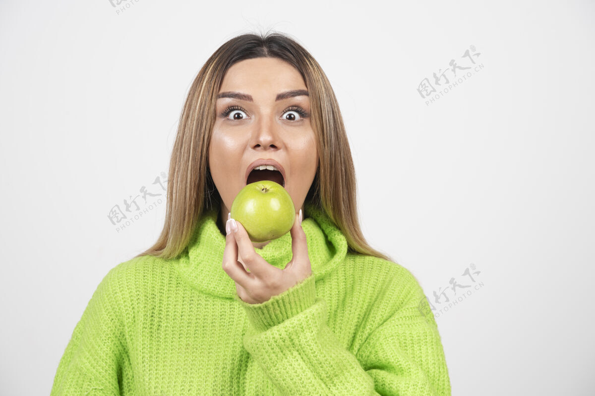 吃穿着绿色t恤的年轻女子正在吃苹果饮食营养绿色苹果