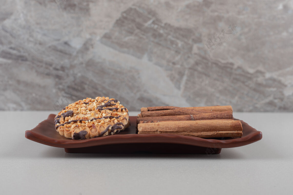肉桂饼干和一捆肉桂棒放在大理石背景的盘子里曲奇香料甜点